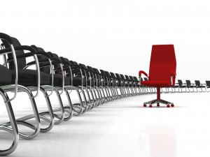 red leader chair with large group of black chairs